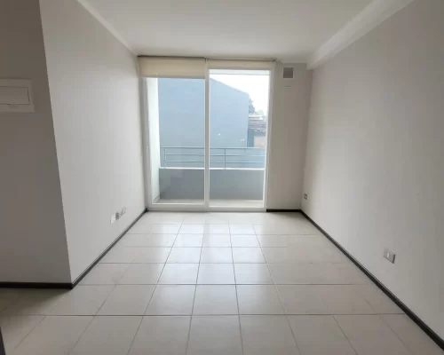 Vista del área de living comedor con piso de cerámica, amplios ventanales y acceso a terraza en departamento nuevo en La Cisterna