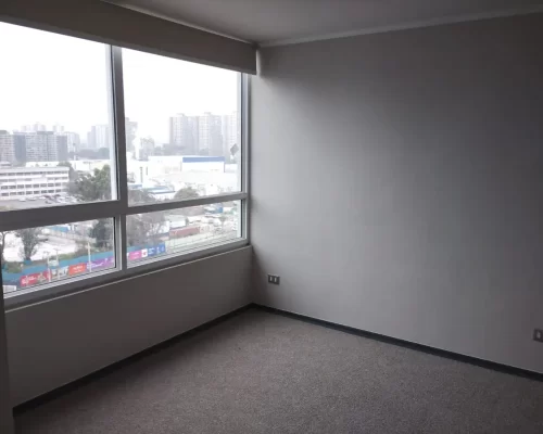 Vista de la entrada al dormitorio alfombrado, mostrando paredes de color neutro y un clóset empotrado con puertas correderas grises.
