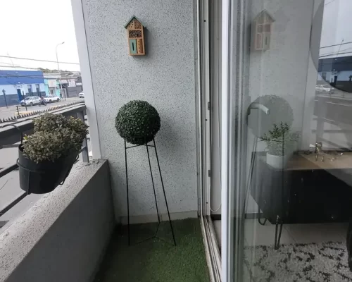 Terraza con piso de pasto sintético, maceteros decorativos y vista despejada hacia el entorno.