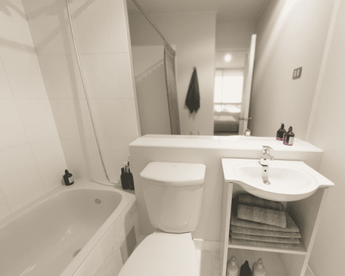 Baño principal en suite con vanitorio moderno, espejo amplio y tina, parte de los acabados de calidad del proyecto.