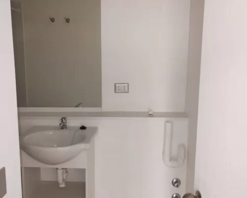 Vista del área de baño que muestra específicamente las conexiones de fontanería preparadas para la instalación de una lavadora