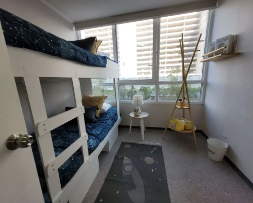 Segundo dormitorio con espacio para cama individual, muros en tonos neutros y piso alfombrado