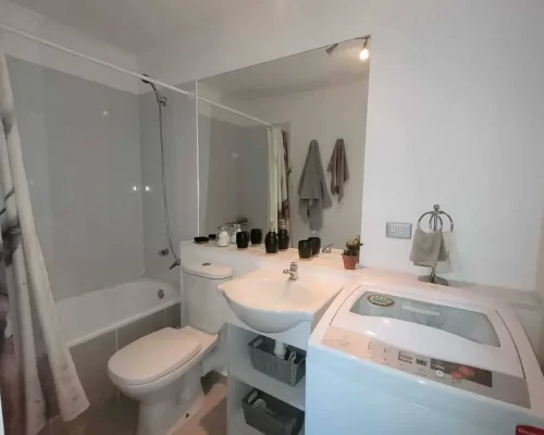 Área del baño que muestra específicamente las conexiones hidráulicas y de desagüe listas para la instalación de una lavadora.